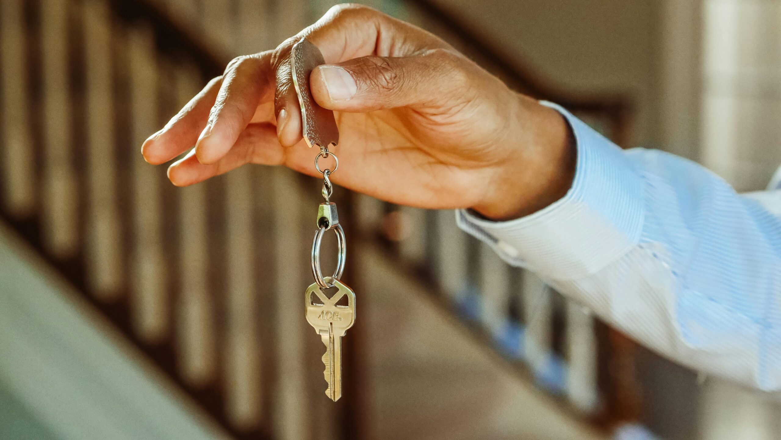 A close-up shot of a hand holding a house key, indicating new ownership or rental.